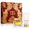 Dolce & Gabbana The One fragrance gift set featuring a red and gold patterned box, a clear glass perfume bottle with golden liquid, and a white body lotion tube with gold accents on a white background.